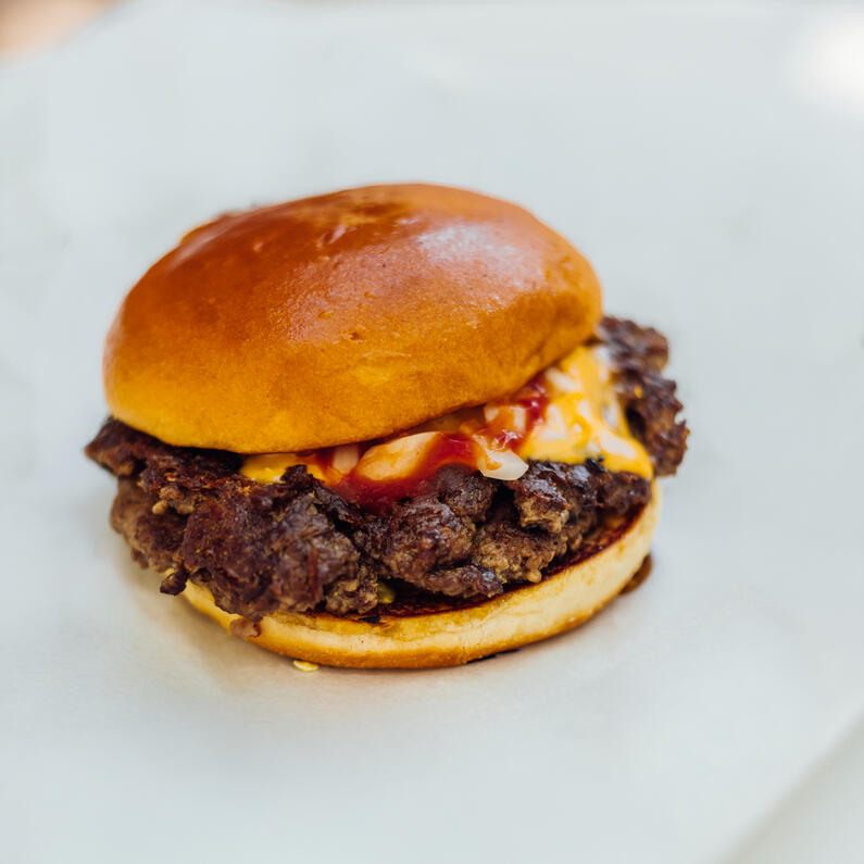 Kleiner Burger mit Beef Patty, geschmolzenem Käse, Zwiebeln und Ketchup im weichen Bun – Kids Burger der Probierbude Hannover.