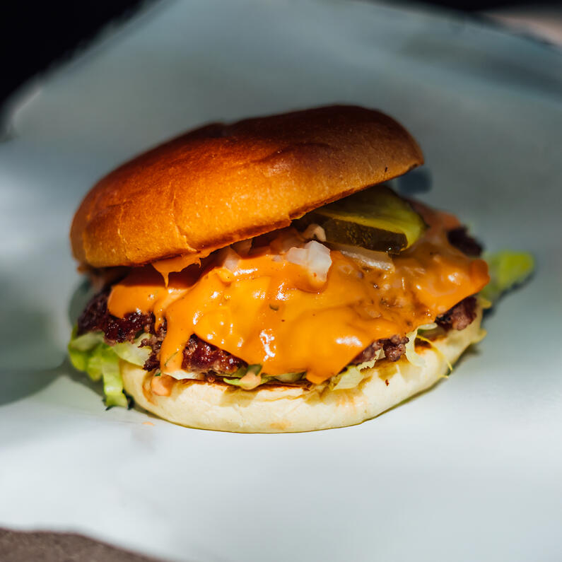 Saftiger Smashburger mit Beef Patty, geschmolzenem Käse, Gurken, Zwiebeln und Salat im Brioche Bun bei der Probierbude Hannover.